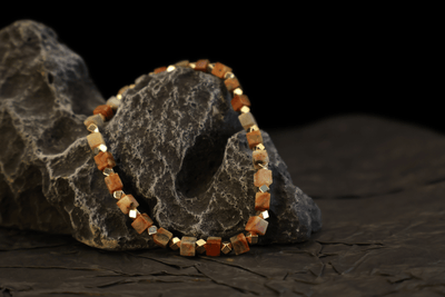 Grounding Colorful Crazy Agate Bracelet I with gold-plated sterling silver cubes draped over a textured dark rock