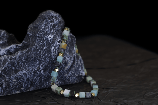 Grounding Multi-Green Amazonite Bracelet I with gold-plated sterling silver cubes draped over a textured dark rock
